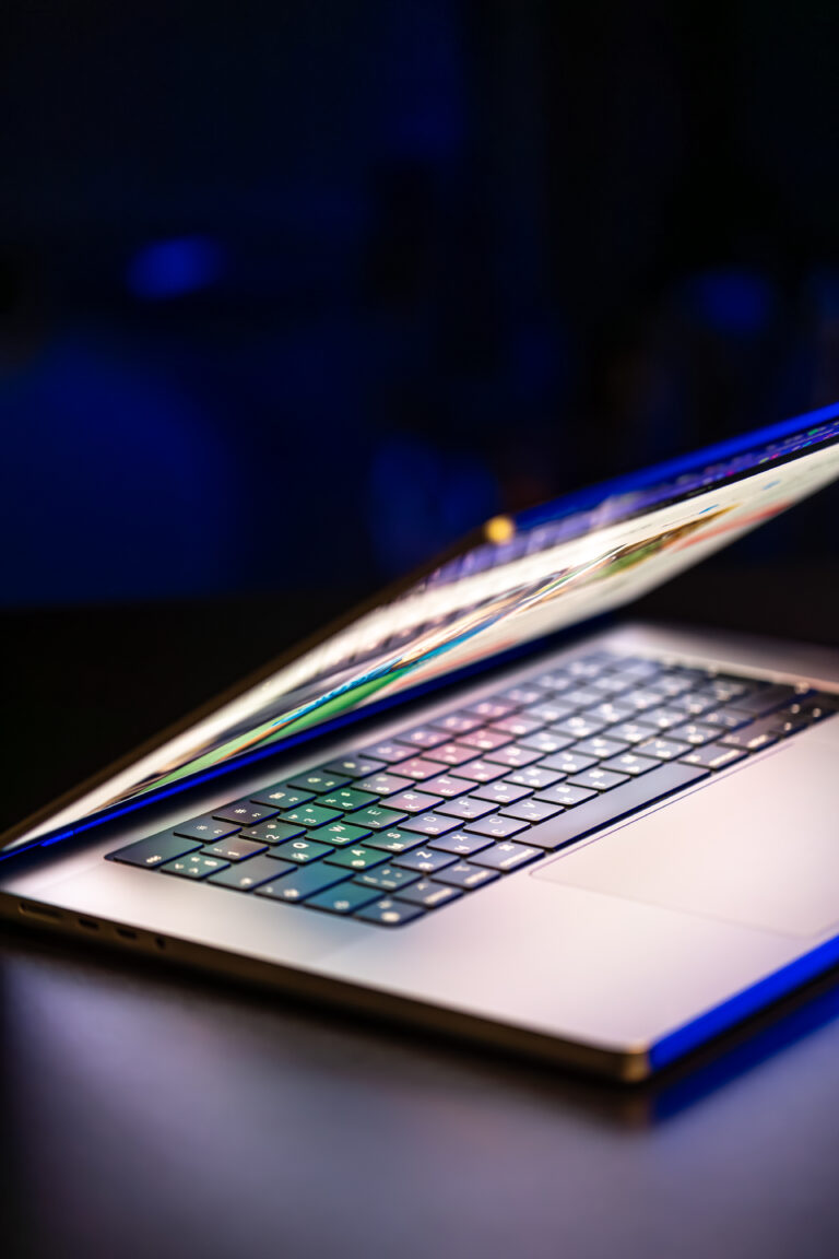 A laptop computer with a half-open screen on a dark background. Copy space